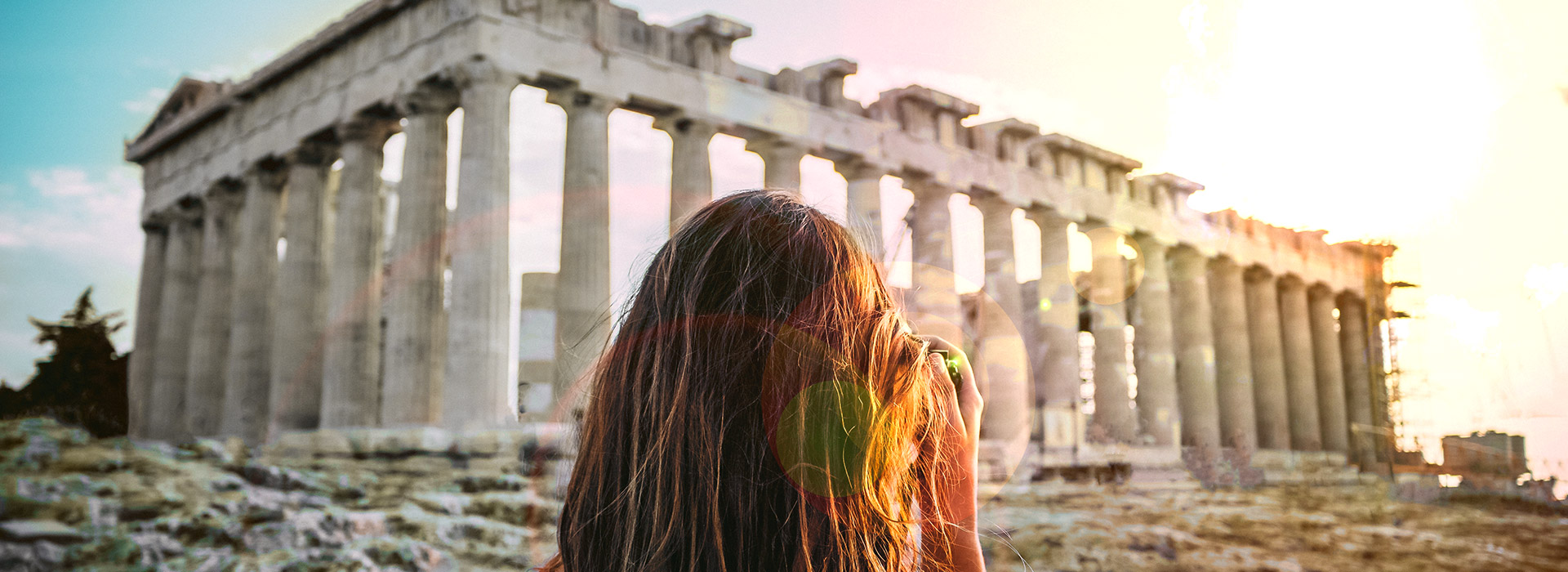 Photo taken behind the head of a woman taking a camera photo of the Parthenon in Greece