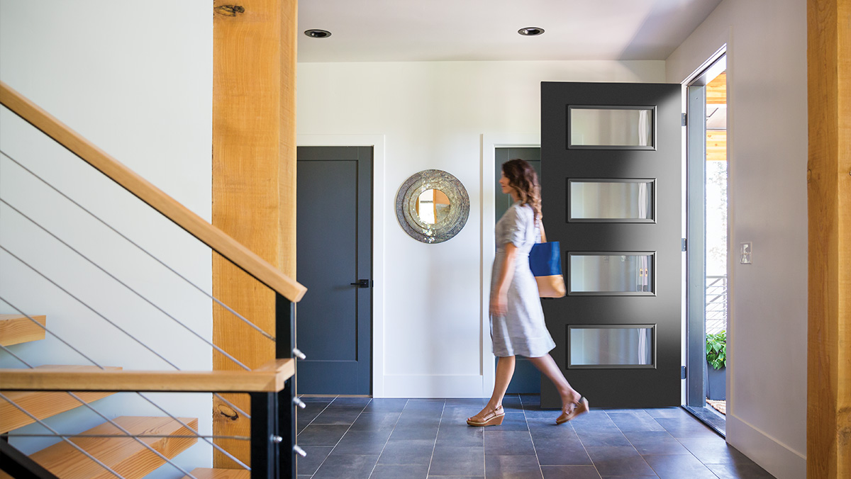Modern style home entryway with a woman walking into the house passing a 4 lite black door