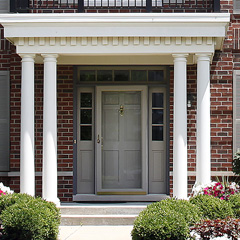 Greek style front porch with a grey 6 panel door with 3 lite 1 panel grey sidelites, 2 round columns on each side and an overhang with dental trim