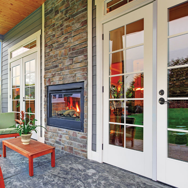 Tradtional style front porch with furniture, an outdoor fireplace and 10 lite white double doors