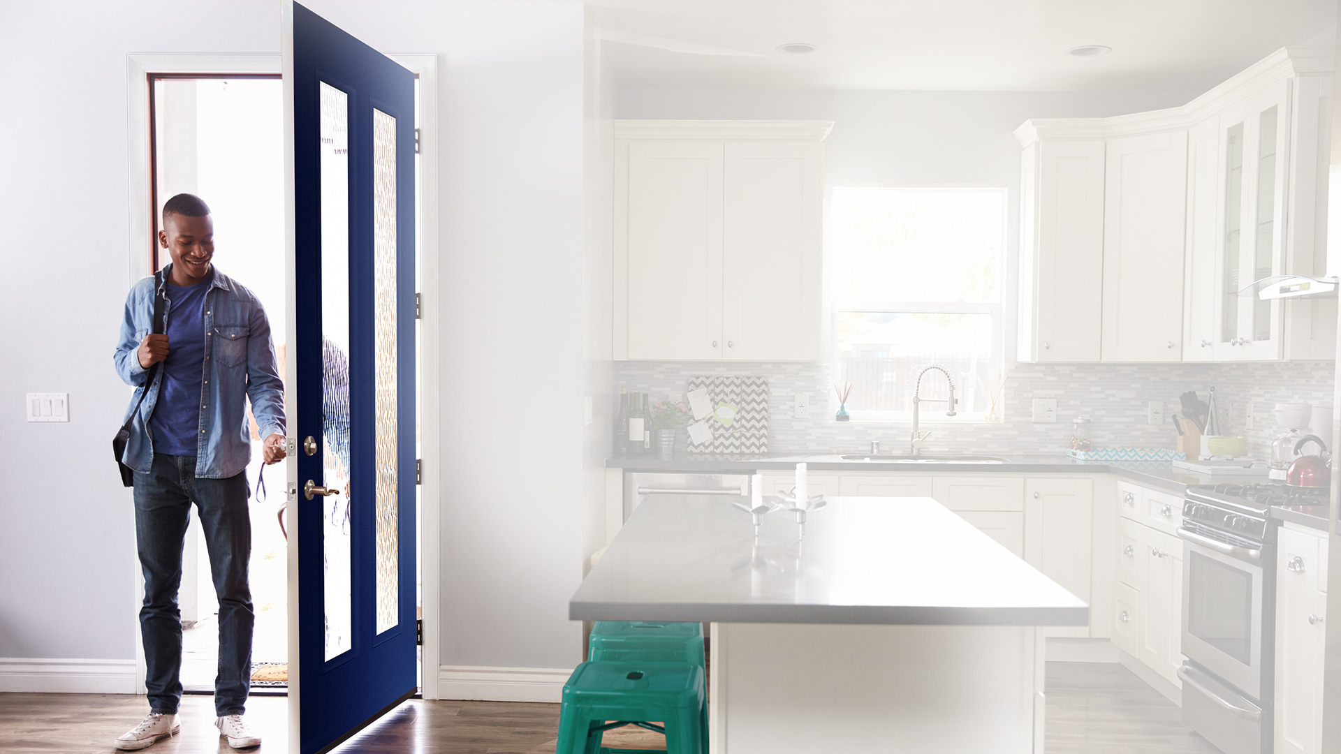 A man is coming into his modern home kitchen with a navy blue 2 vertical lite front door