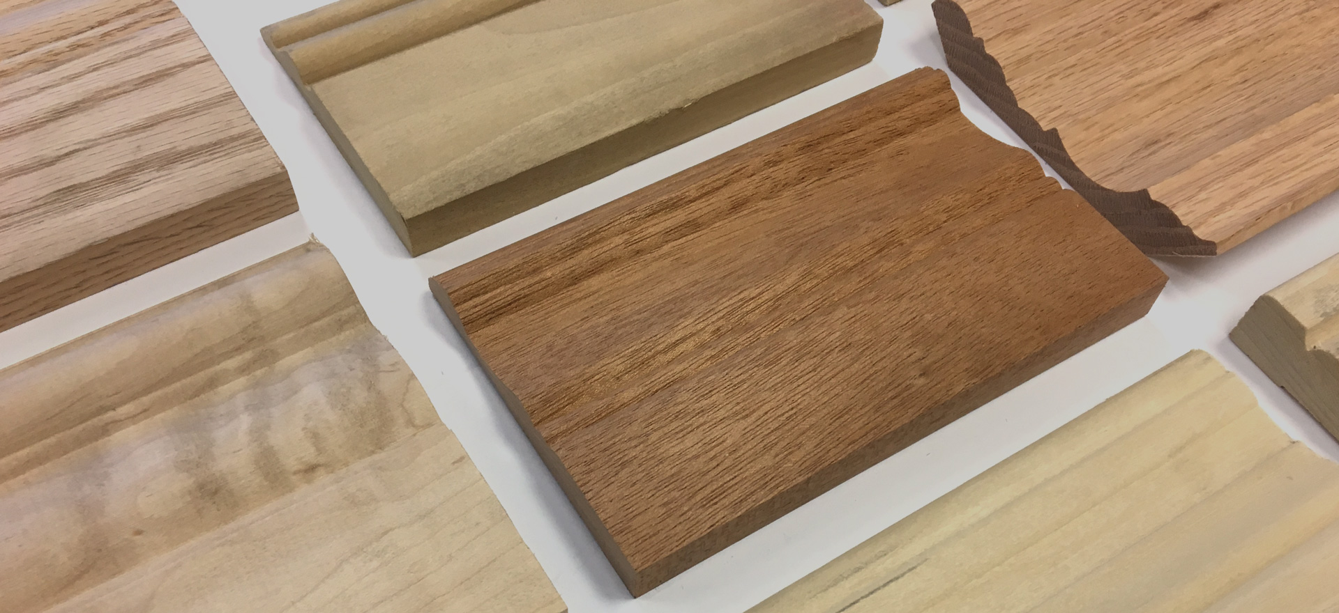 Pieces of hardwood moulding  samples in different species laid out on a white table