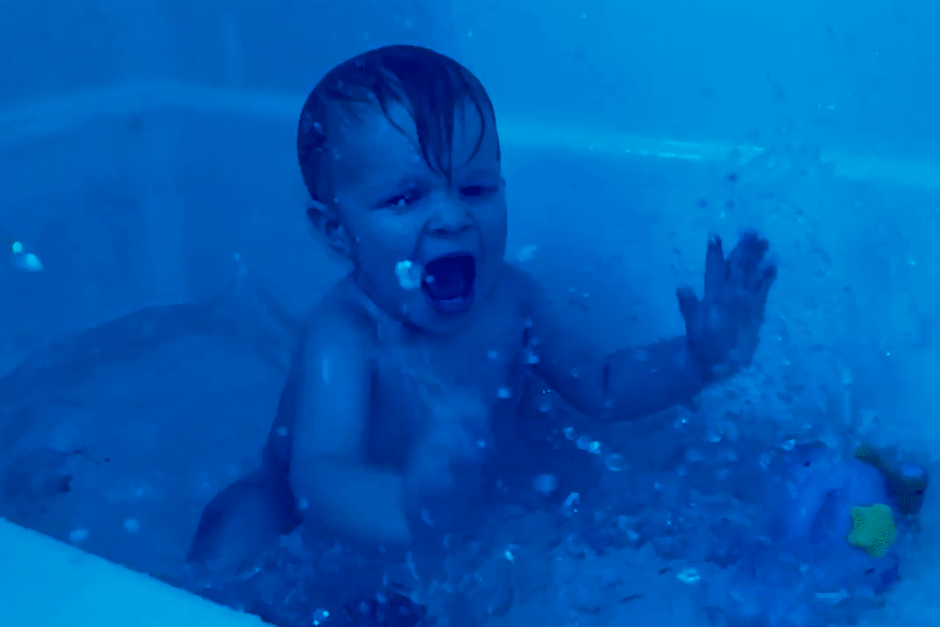 Blue haze over a video of  a young child splashing in the bath