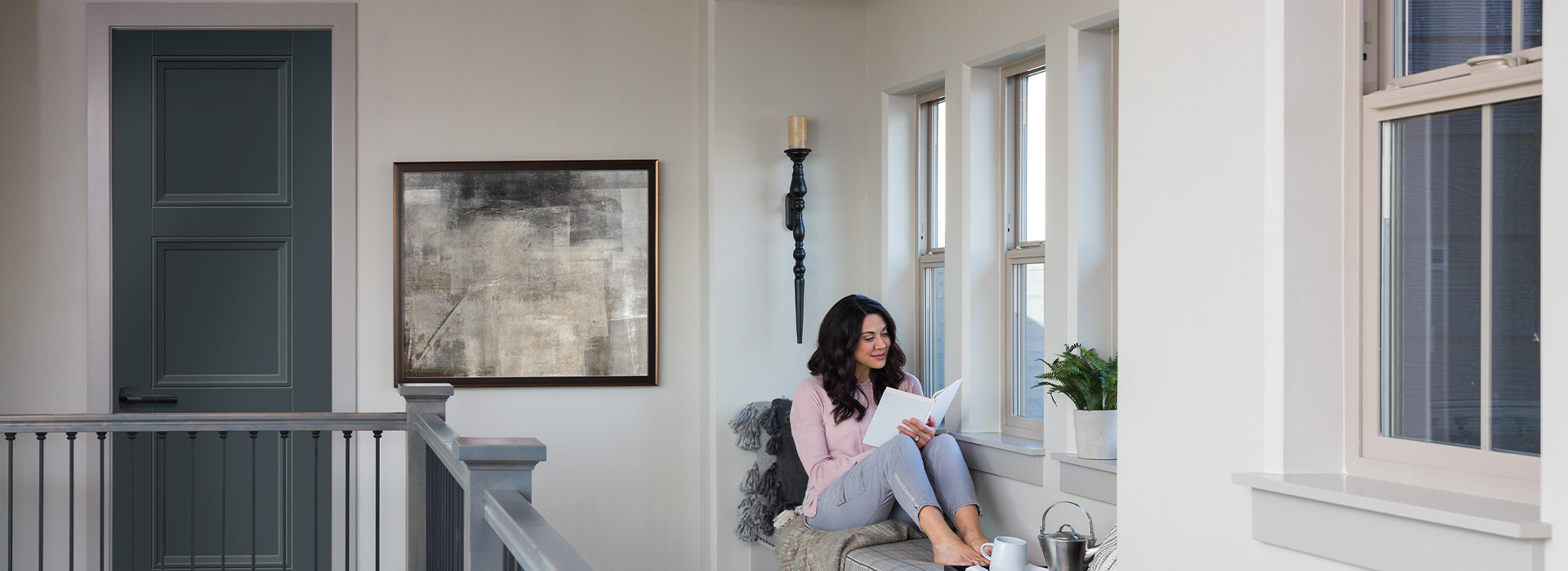 Woman sitting and reading next to a window in the 2nd floor of a house next to an interior 3 square panel Livingston door