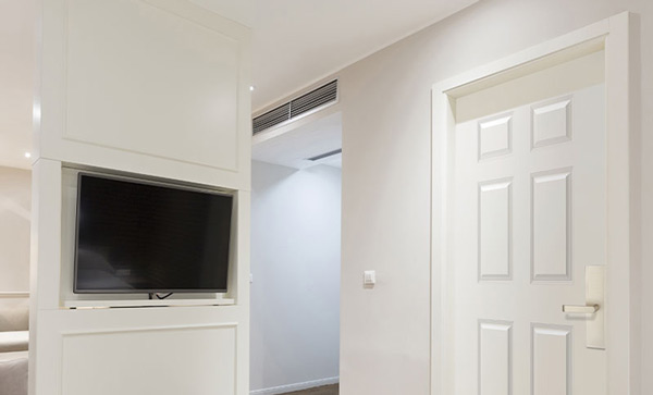 White room with a6-panle door on the right and a television on the left