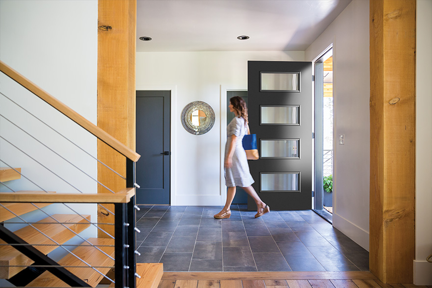 Woman walking into a Modern style home past the 4 lite black modern door