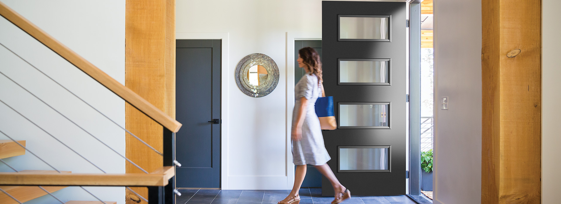 Woman walking into a Modern style home past the 4 lite black modern door