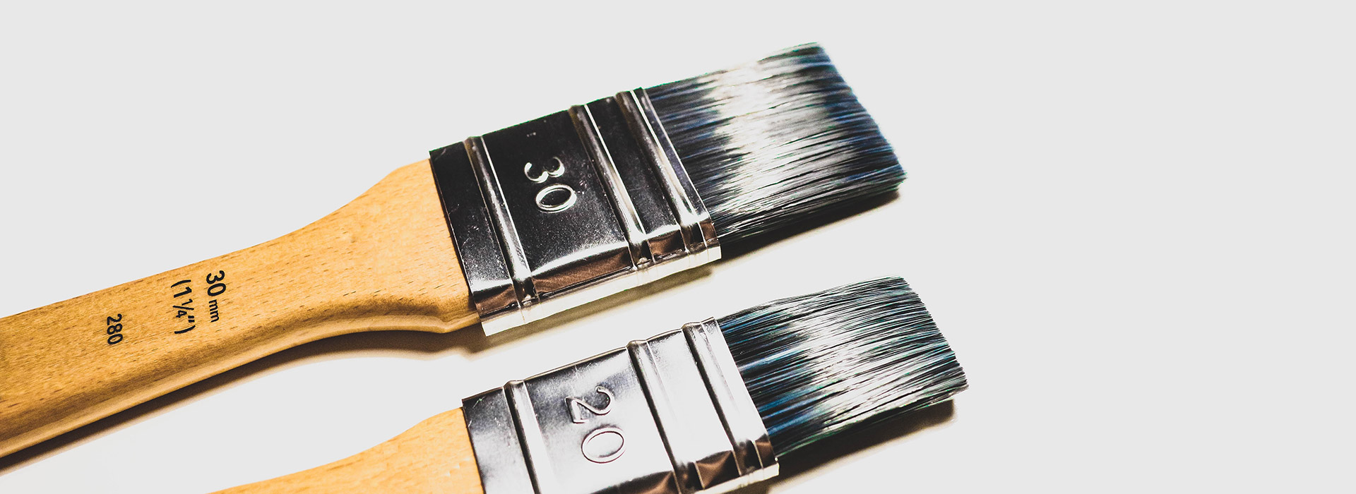 2 paint brushes, 30 mm and 20 mm, are laid on a white surface
