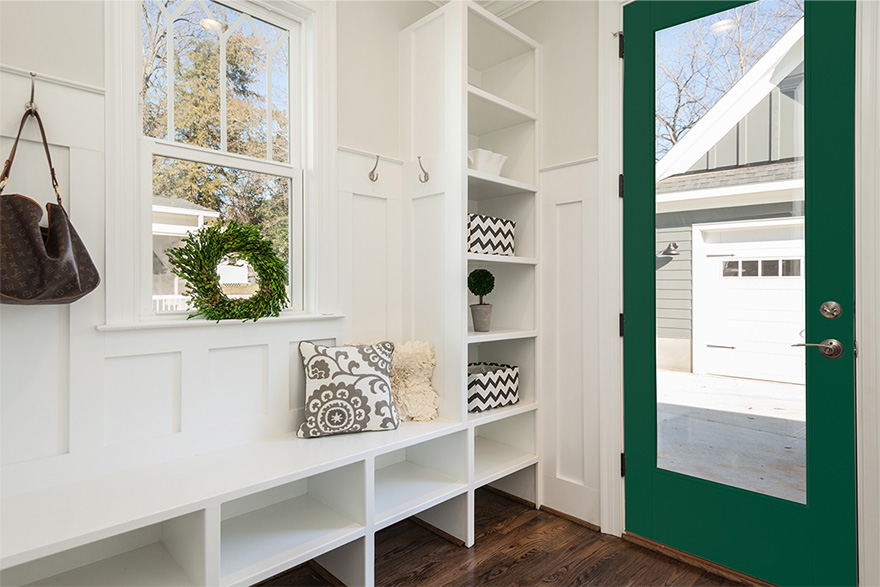 A white mudroom in a modern farmhouse style home with a VistaGrande full lite green door