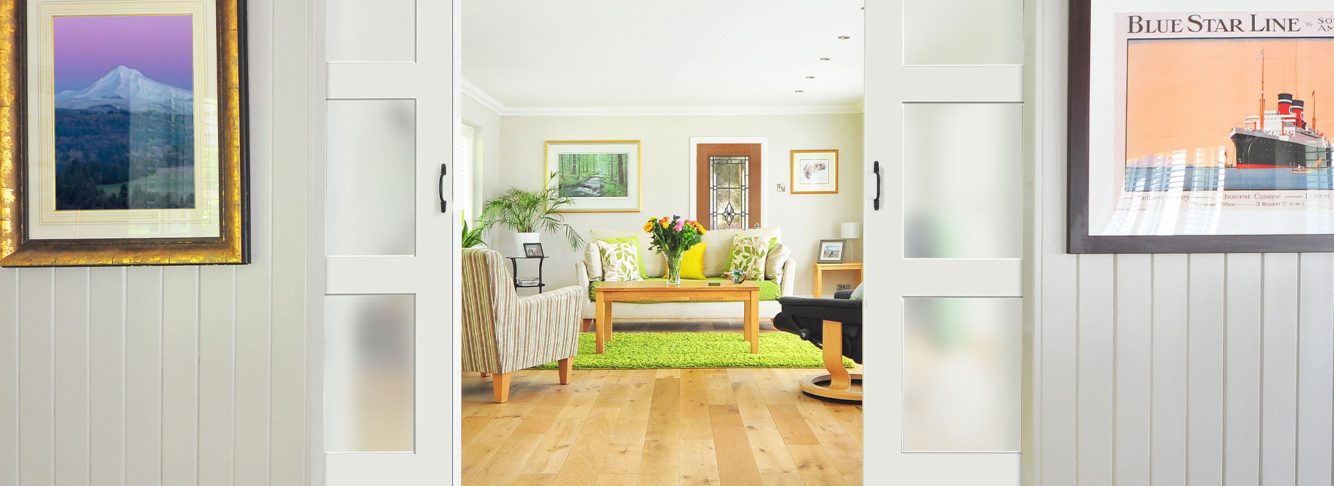 Sliding double doors entryway view of a Modern Cottage style living room with 3 sofas around a green shag rug under a wooden rectangle coffee table in the center of the room