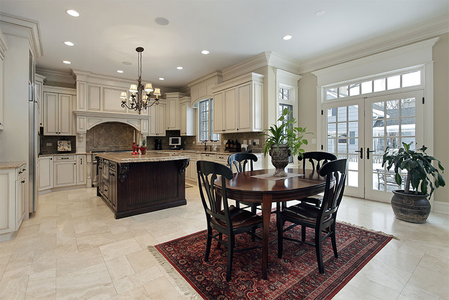 Craftsman style kitchen with grey walls, white crown moulding, white cabinets and drawers, white marble counter tops, stainless steel appliances, and a center island with 2 brown square stools tucked under