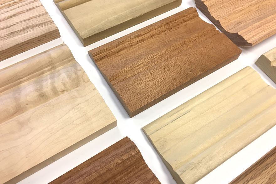 Different species samples of baseboard moulding laid on a white table