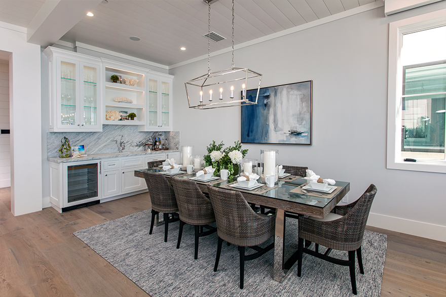 Coastal style dining area with a white shiplap accent ceiling and a rectangle dining table with 8 chairs