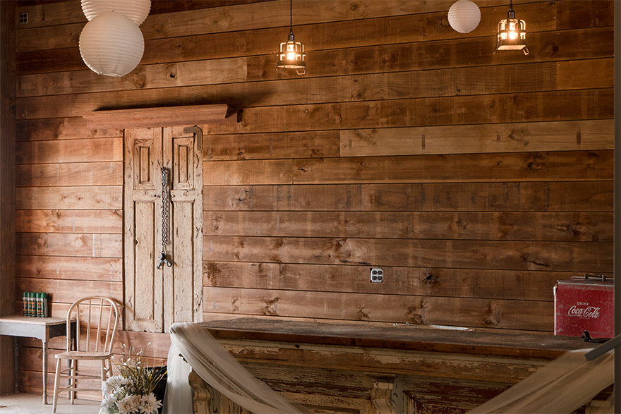 Rustic style hall with a shiplap accent wall, wooden bar, and wooden window decorated with string lights and paper bulbs
